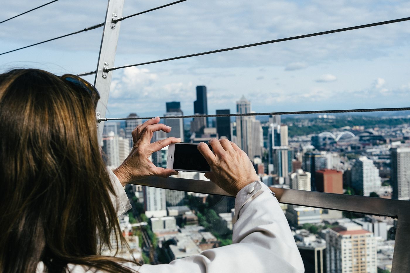 A woman photographing a city skyline with her phone